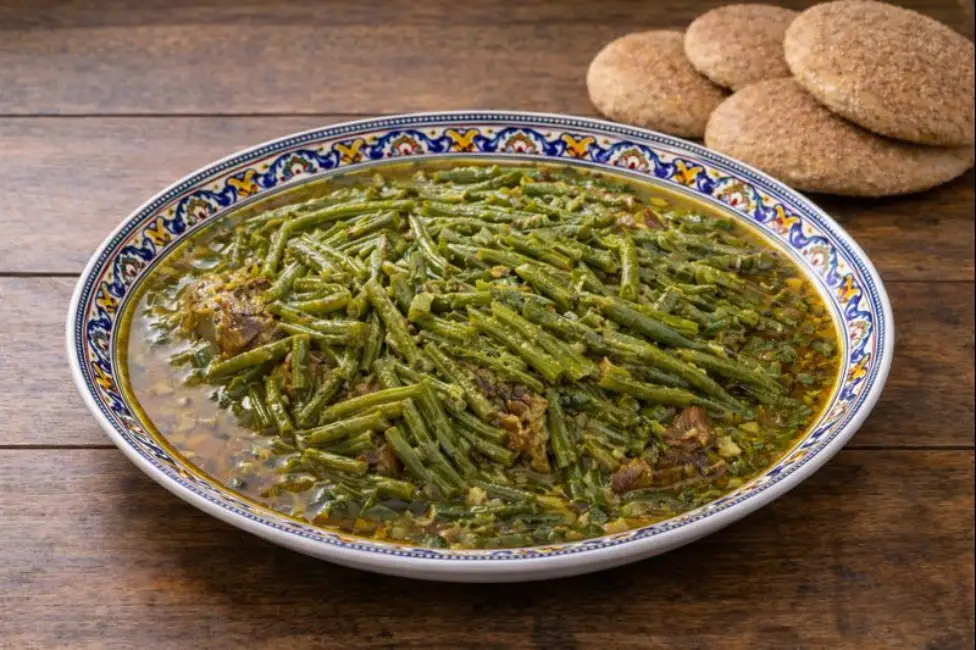 Moroccan beef and green beans served on a decorated ceramic plate with traditional Moroccan bread.