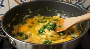 A pan of golden eggs being mixed with caramelized onions for Moroccan Bastilla.