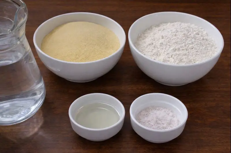 Ingredients for preparing trid dough — semolina, flour, salt, oil, and water — arranged on a wooden table for a typical Moroccan meal like Rfissa.