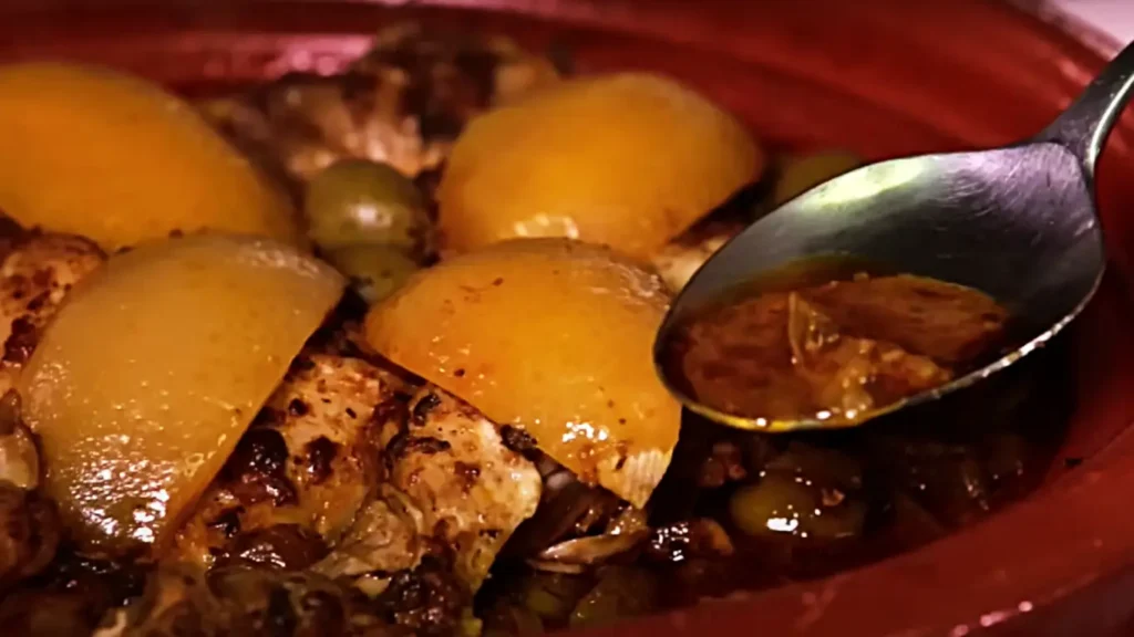 A close-up shot of a spoon scooping the rich, thick 'Daqhmira' sauce from the Moroccan chicken tagine.