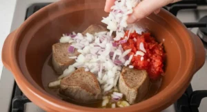 Stirring onion and tomato into lamb base for Moroccan okra recipe